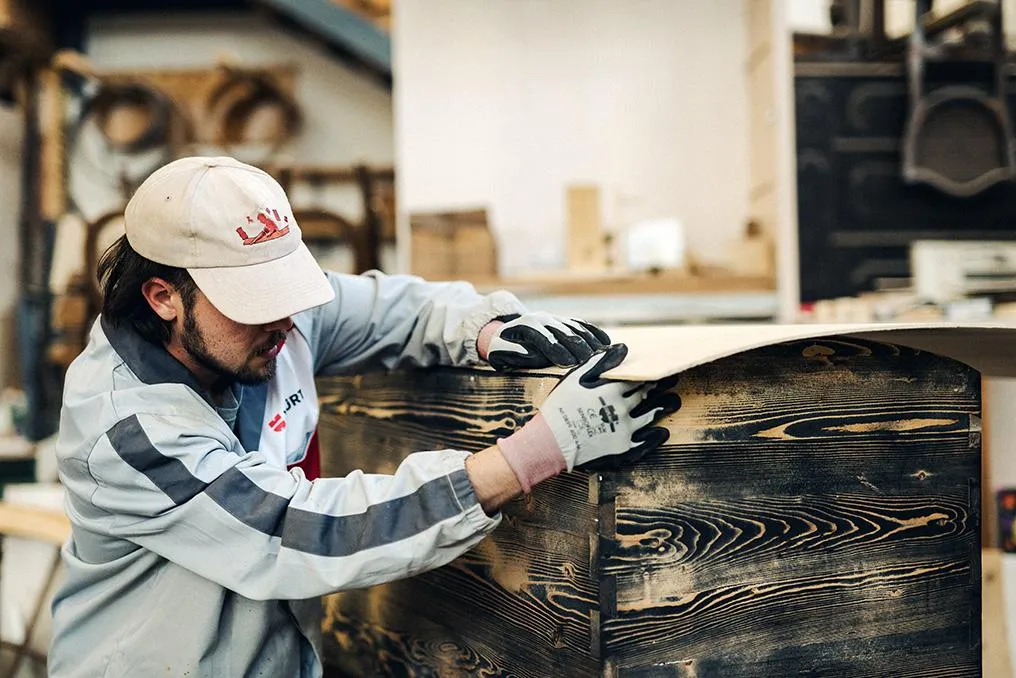 Artigiano al lavoro su un pannello in legno nella bottega