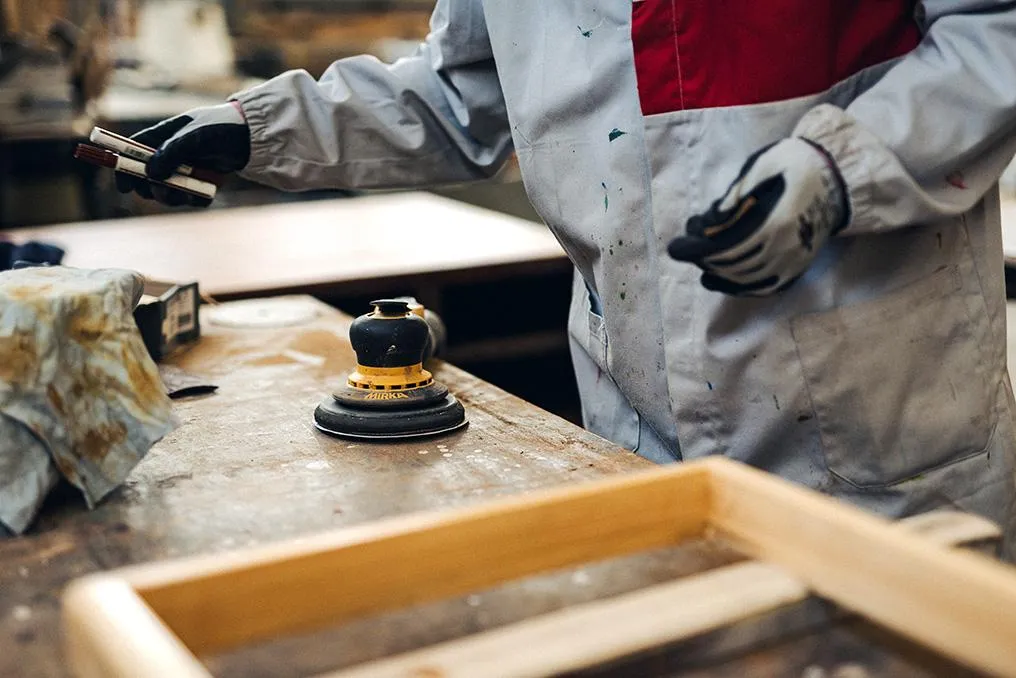 Artigiano leviga un manufatto in legno al banco da lavoro